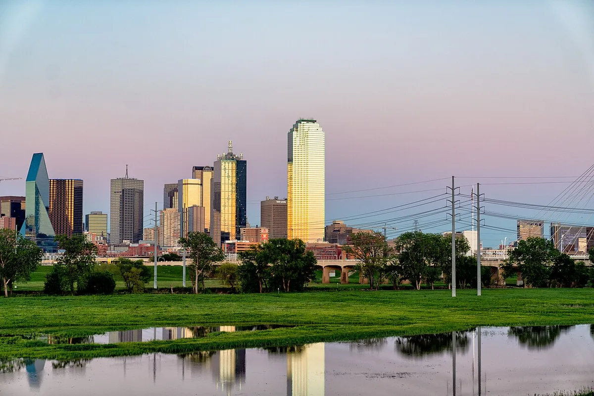 Dallas skyline across the Trinity River, with electrical lines in the foreground.
