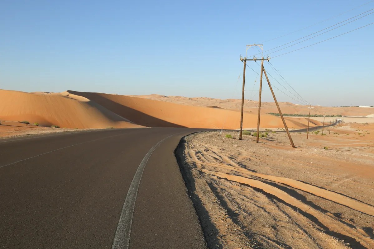 A road and power lines through the dunes of Liwa in Abu Dhabi.