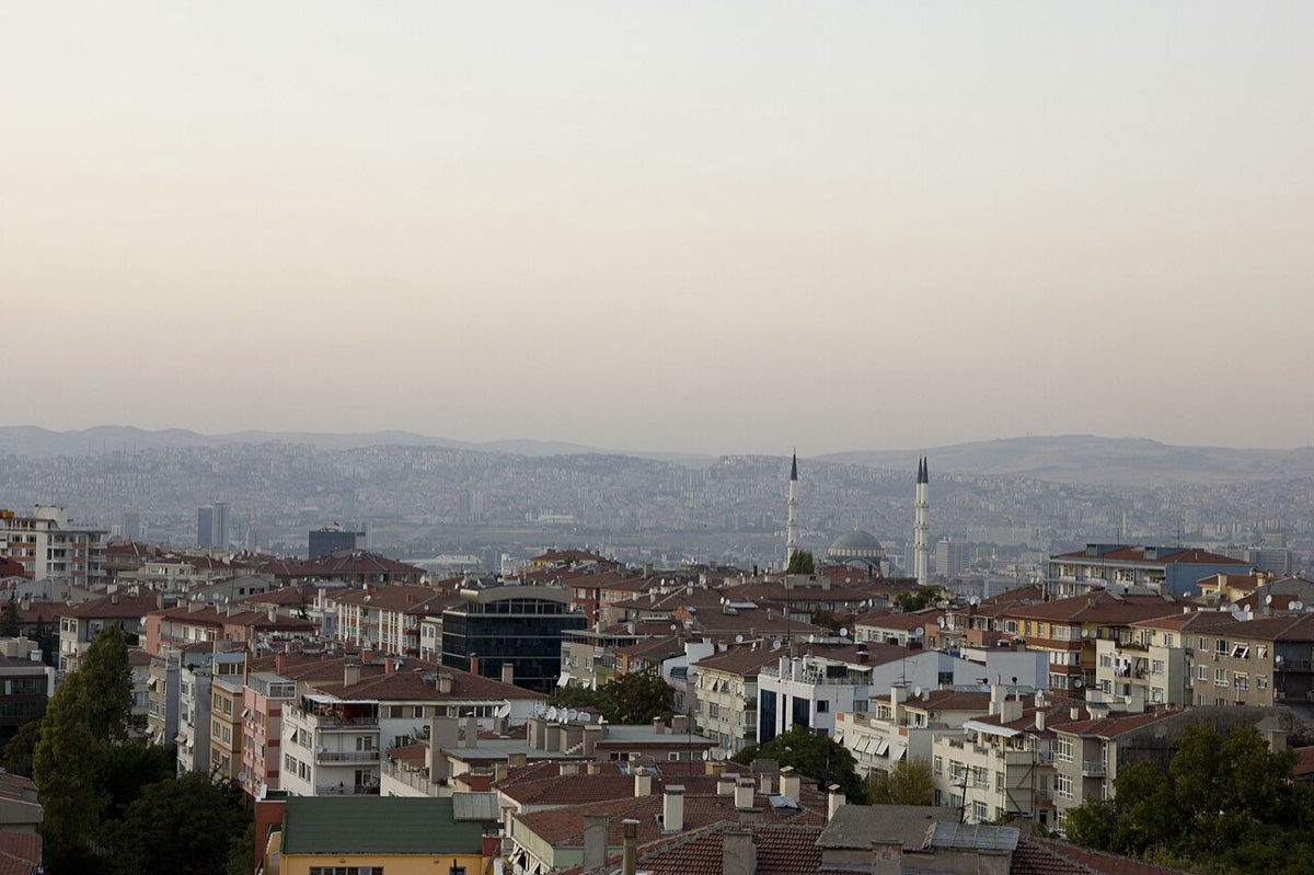 Ankara at dusk, dense housing in the foreground and the city stretching to the hills.